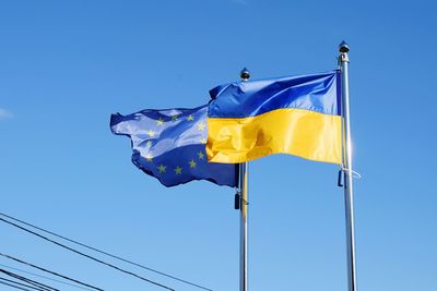 Low angle view of flags waving against blue sky