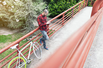 High angle view of man standing by railing with bicycle