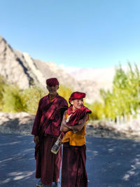 Boy and woman in traditional clothes while standing on road against sky