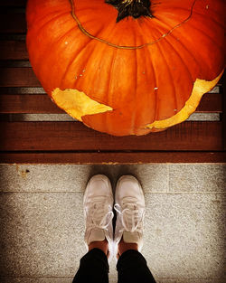 Low section of person standing by pumpkin