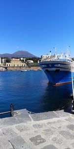Boats moored in sea against clear blue sky