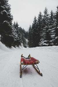 Red umbrella on snow covered field against sky