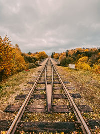 Railroad tracks amidst trees against sky during autumn