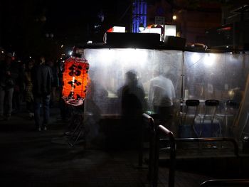 People standing on illuminated street at night