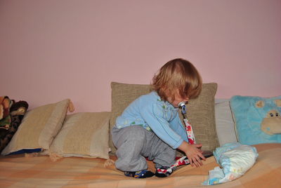 Close-up of boy crouching on bed at home