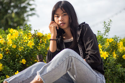 Portrait of young woman against flowering plants