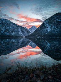 Scenic view of lake by mountains against sky during sunset