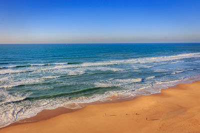 Scenic view of beach against clear blue sky