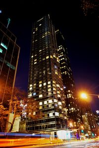 Low angle view of illuminated cityscape against sky at night