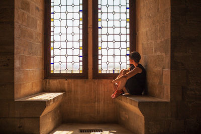 Rear view of a young man looking through window