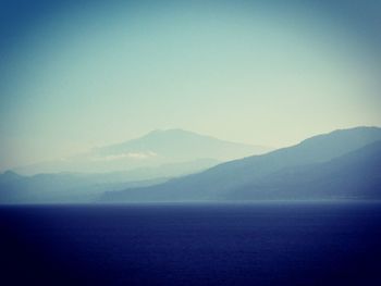 Scenic view of sea and mountains against clear sky