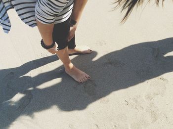 Low section of woman folding leggings while bending at beach