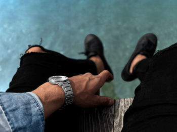 Low section of man sitting on pier over sea