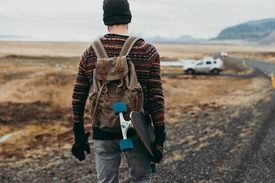 Man walking with skateboard on highway