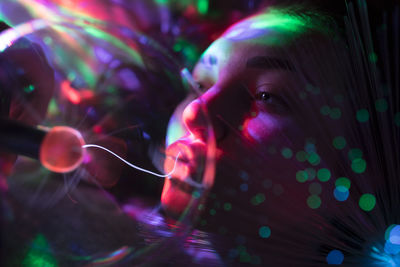 Close-up of woman seen through illuminated bulb by fiber optic in nightclub