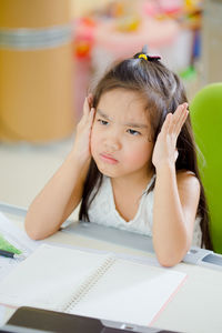 Portrait of girl sitting on table