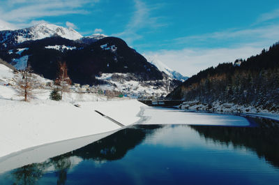 Scenic view of lake by snowcapped mountains against sky