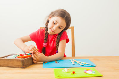 Cute girl holding toy while sitting on table