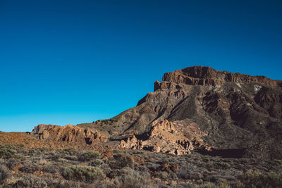 Rock formations on mountain against blue sky