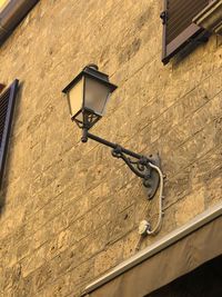 Low angle view of street light hanging on wall of building