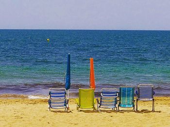 Chairs on beach against clear sky