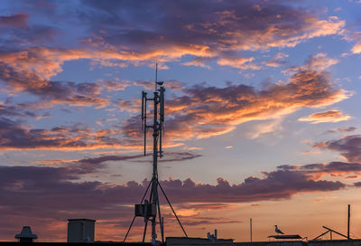 Low angle view of silhouette cranes against sky during sunset