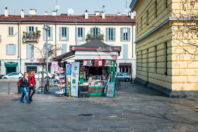 People walking on street amidst buildings in city