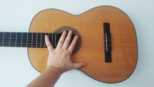 Cropped hand of person touching guitar on table