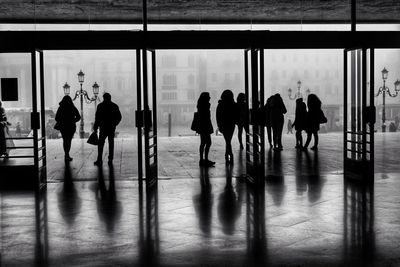 Silhouette people walking on glass window