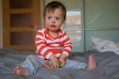 Cute boy with toy sitting on bed