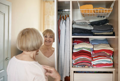 Rear view of woman standing in front of mirror at home