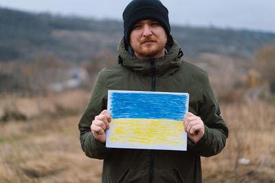 Ukrainian man holds a painted flag of ukraine. war of russia against ukraine.