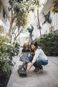 Mother and girl with arms raised while standing on tree