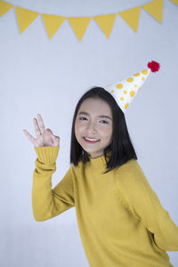 Portrait of smiling young woman standing against wall