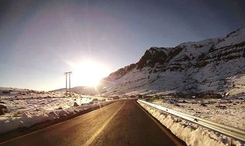 EMPTY ROAD LEADING TOWARDS SNOW COVERED MOUNTAINS