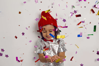 Portrait surprise in knitted hat boy child in silver shirt and red bow tie catches glitter confetti