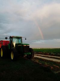 Scenic view of agricultural field against rainbow in sky