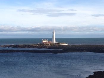 Lighthouse by sea against sky