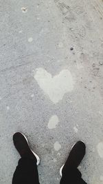 Low section of man standing on heart shape on street