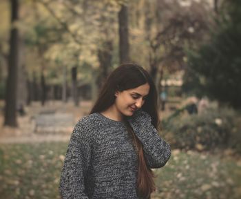 Young woman with arms raised against trees