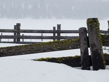 Snow covered railing against sky