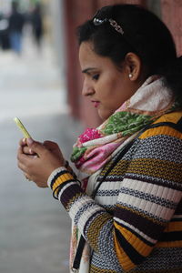 Woman using mobile phone against wall