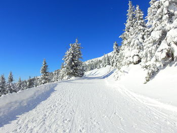 Snow covered landscape against clear blue sky