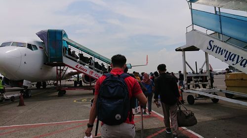 Rear view of people on airplane against sky