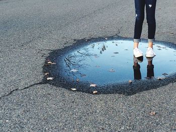 Low section of woman standing on puddle