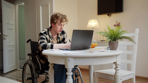 Young disabled man working at home office