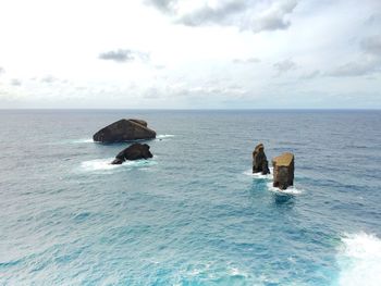 Scenic view of rocks in sea against sky