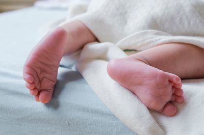 Low section of baby lying on bed