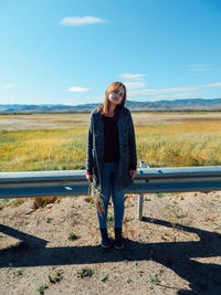 Portrait of woman standing by crash barrier against sky