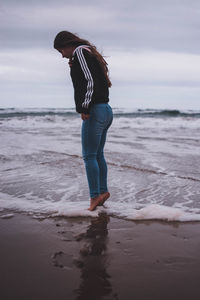 Full length of woman standing on beach against sky